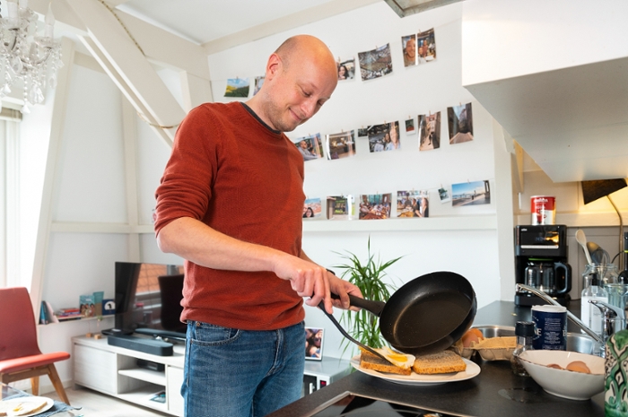 Computer scientist and psychologist Roy de Kleijn fries an egg in the kitchen in his flat.