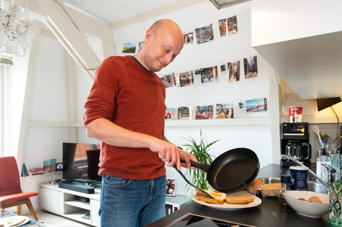 Computer scientist and psychologist Roy de Kleijn fries an egg in the kitchen in his flat.