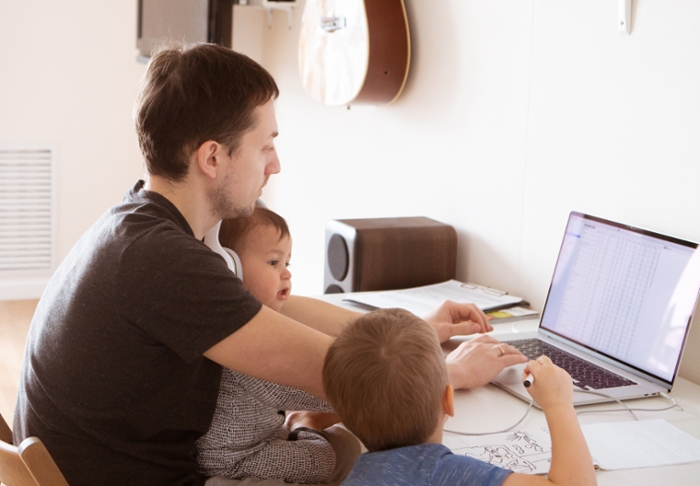 Father with two small children trying to work at his laptop