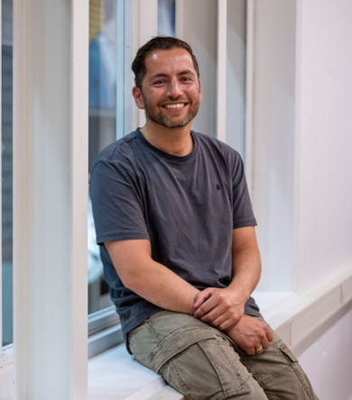Youri Smeltink looks smiling into the camera, sitting in a window frame.