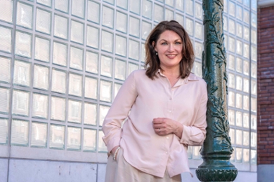 Claudia Bouteligier leans against a lamppost, posing in front of the Kamerlingh Onnes Building.