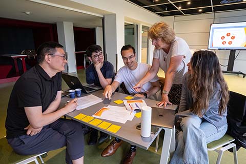 Honours students of a master's course have a discussion other with infographics in the background.