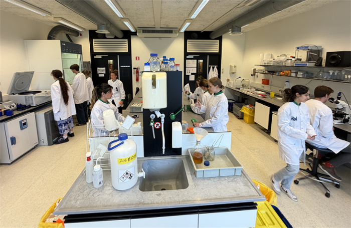 The iGEM team, all wearing white lab coats, working in their lab