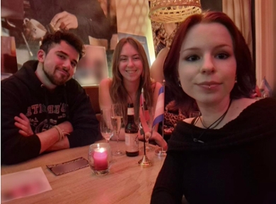 three students sitting at a table in a cafe and all look in the camera